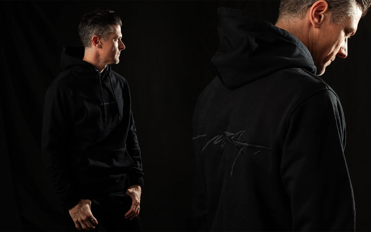 Two men in black Stark Future hoodies with small logos, in a dark studio.